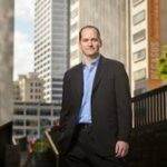 A man in a business suit standing in front of tall buildings representing a digital marketing agency.